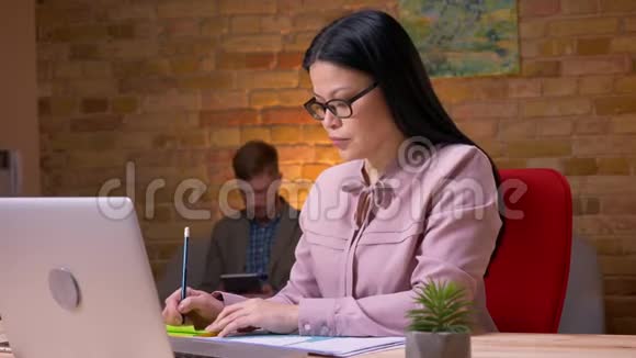 亚洲成年女商人的特写镜头她在笔记本电脑上工作为坐在电脑前的商人处理图表视频的预览图