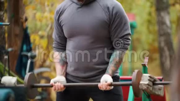 一位健美运动员用砖头和砝码做成的哑铃抽手户外运动训练视频的预览图