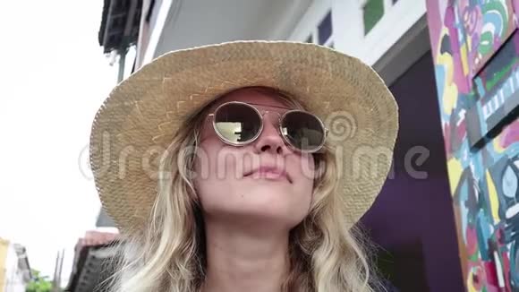 一个年轻漂亮的金发女人戴着草帽和时髦的太阳镜的肖像视频的预览图