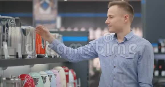 年轻英俊的男人选择一个电水壶来买检查设备检查价格标签和视频的预览图