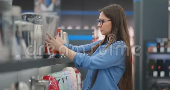 年轻漂亮的黑发女人选择了一个电水壶来买检查设备检查价格标签和视频的预览图