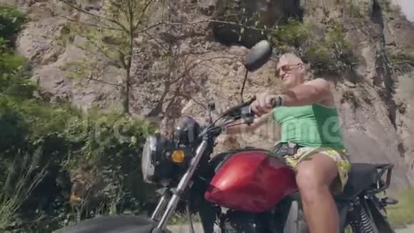 夏天旅行时野蛮人骑摩托车在公路上欣赏山景关闭高级摩托车手视频的预览图