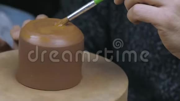 陶工用刷子给水壶上油以固定盖子手工陶土茶壶用于茶道棕色陶瓷茶壶4k视频的预览图