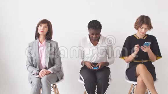 三个女商人希望在办公楼走廊的椅子上接受采访视频的预览图