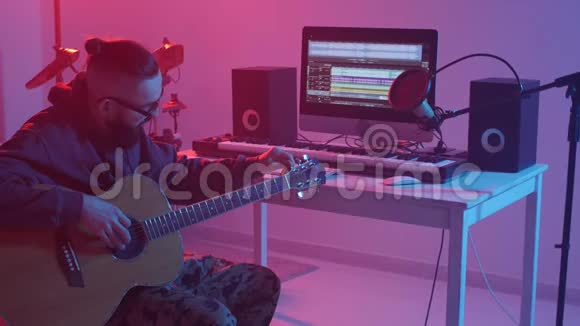 爱好和音乐的概念一个留胡子的年轻人在一家音乐工作室弹吉他视频的预览图