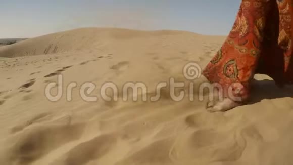 女孩赤着脚穿着五颜六色的裙子走在沙滩上把它扔到沙漠里视频的预览图