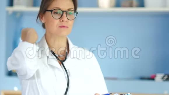 严肃的女医生穿着白色外套和眼镜手里拿着一个文件夹在办公室的墙壁上医学和医学视频的预览图