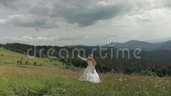 美丽的新娘穿着婚纱留在山上抬起她的手视频的预览图
