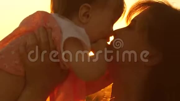 年轻美丽的母亲带着孩子在空中玩耍在金色阳光的夕阳下笑着慢动作视频的预览图