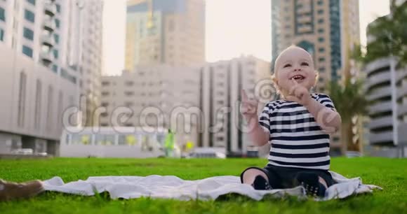 快乐的小孩子坐在草地上有着白色的雏菊城市背景视频的预览图