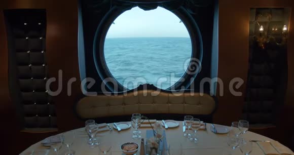 在游轮上巨大的圆窗背景下餐馆里的一张餐桌视频的预览图