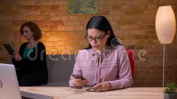 成人亚洲女商人在办公室内的笔记本电脑前通过电话在线购物的特写镜头视频的预览图