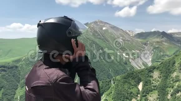 戴摩托车头盔的男子游客在绿白种人山区的旅游理念中放眼望去视频的预览图