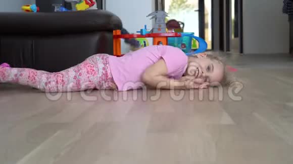 可爱的小女孩金发在地板上滚动到相机关节活动度射击视频的预览图