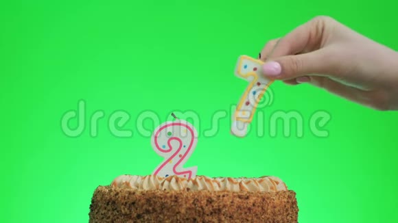 在一个美味的蛋糕上放27个生日蜡烛绿色的屏幕视频的预览图