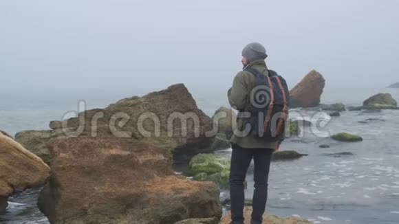 一个孤独的成年男子在散步时的后景四处看看野生海边的美景视频的预览图