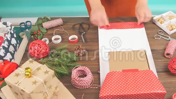 女性双手将圣诞礼物包裹在工艺生态纸上的深色木制背景带有装饰元素视频的预览图