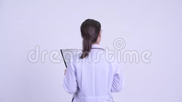 年轻女医生手指在剪贴板上阅读的后视图视频的预览图