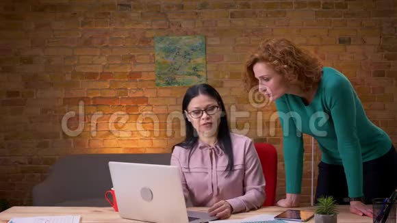 两个女商人在办公室里讨论笔记本电脑数据的特写镜头商人路过视频的预览图