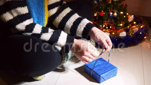 这位年轻女子用蓝纸和丝带包装圣诞礼物特写视频的预览图