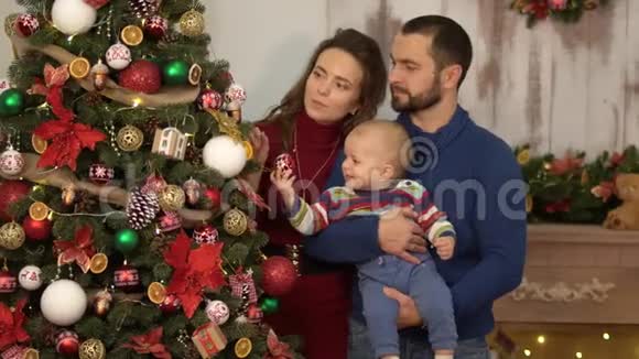 母亲父亲和一个婴儿在装饰圣诞节的房间里玩得很开心爸爸和妈妈玩小孩扔他视频的预览图