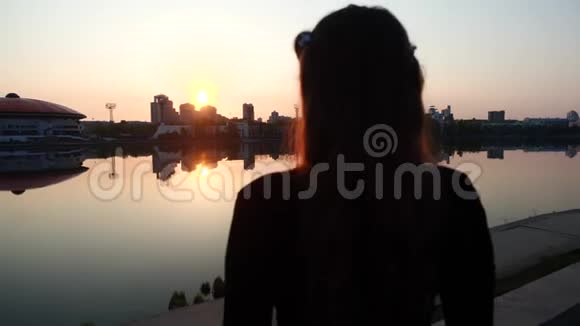 一个女孩背对着镜头站在夕阳下的轮廓视频的预览图