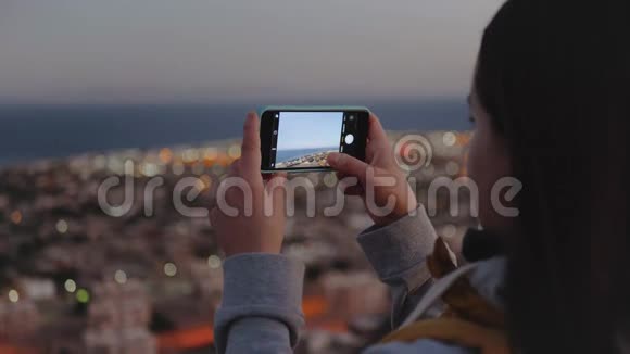 晚上女人用智能手机拍海女人呆在山顶眺望地平线视频的预览图