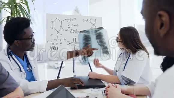 一群多民族的专业医生正在讨论一张病人肺部x光而他们却坐在视频的预览图