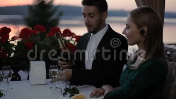 两个金发女郎和两个男人在户外露台上的一家夏日咖啡馆里浪漫地约会俯瞰湖面视频的预览图
