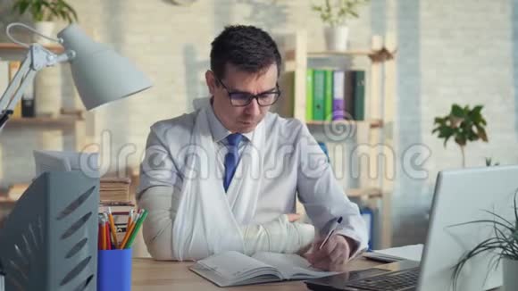 一位戴眼镜手臂骨折的男性办公室工作人员的肖像视频的预览图