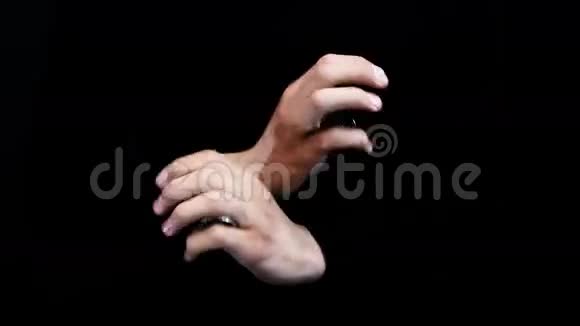 魔术师在黑色背景下表演硬币魔术视频的预览图