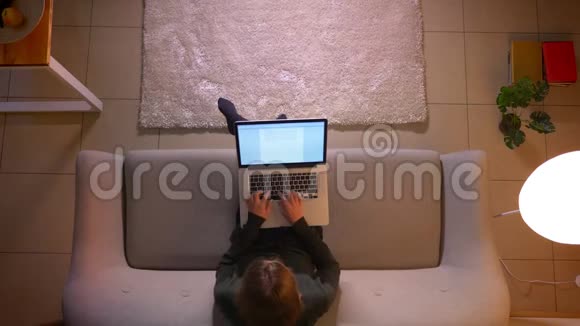 年轻漂亮的女商人在舒适的家里坐在沙发上用笔记本电脑打字的特写镜头视频的预览图