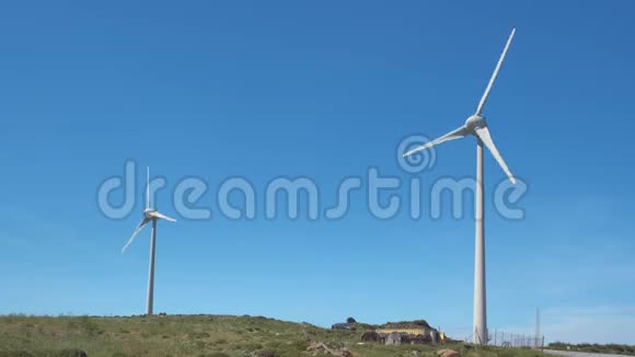 阳光明媚的一天两台风力涡轮机和山景之间的道路对角线拍摄视频的预览图