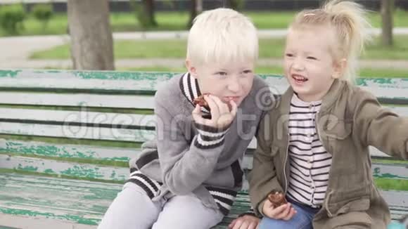 可爱的孩子们坐在公园的长凳上视频的预览图