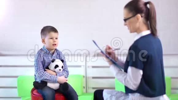 微笑年轻的职业女性心理学家与小男孩交谈心理健康视频的预览图