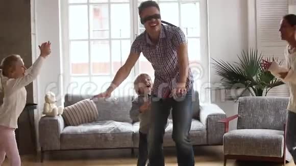 带着蒙眼的父亲玩躲闪和拍手游戏的快乐家庭视频的预览图