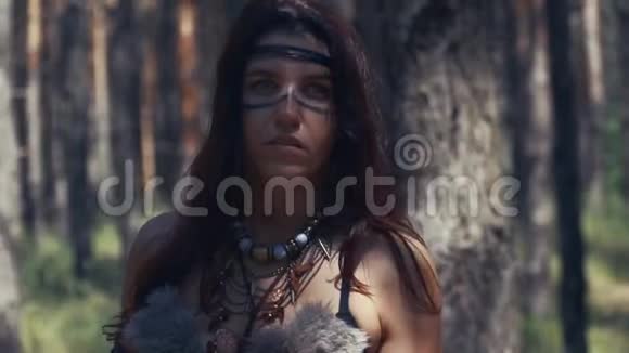接近一个年轻的亚马逊战士在树林里涂面漆视频的预览图