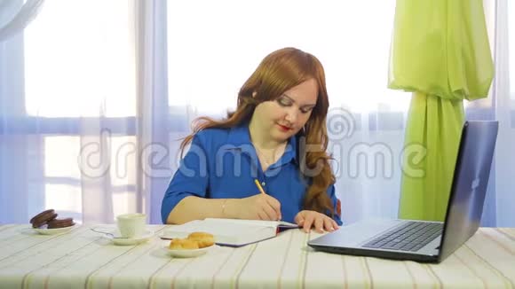 一个棕色头发的女人在一个咖啡馆里在一张桌子上用笔记本电脑工作视频的预览图