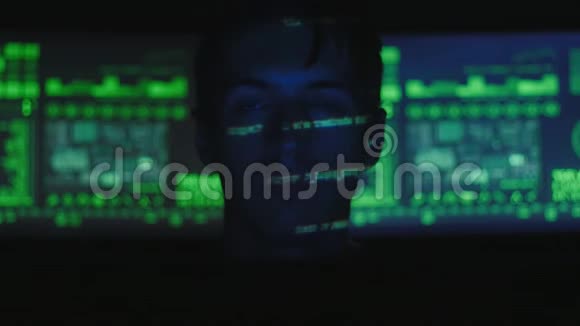 黑客程序员在计算机上工作而绿色代码字符在网络安全中心反射他的脸视频的预览图