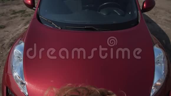 漂亮的女人把头发理直堆放在一辆红色汽车的引擎盖上4K慢慢视频的预览图