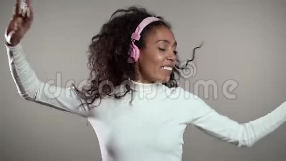 非洲女人卷发开心微笑戴着耳机跳舞视频的预览图
