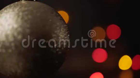 杰克把注意力集中在前景的银色圣诞球上闪烁的圣诞灯在背景上闪闪发光特写镜头视频的预览图