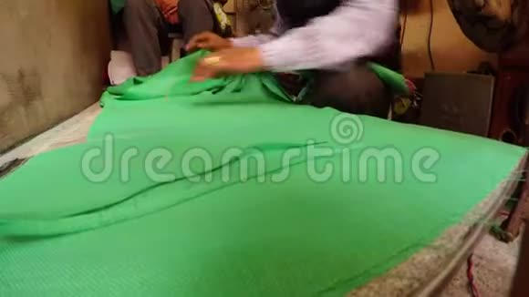 双手在桌子上铺上绿色布把印度缝纫车间的布贴上视频的预览图