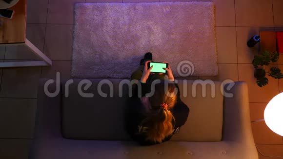 在沙发上坐着用手机玩电子游戏看电视的漂亮少女特写镜头视频的预览图