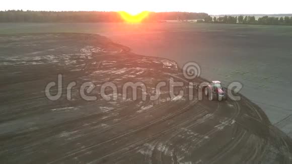 在夏季的空中景色中拖拉机在日落时犁出广阔的田野视频的预览图