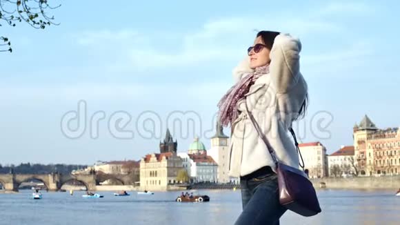 微笑美丽的女人在堤岸上摆姿势观赏历史建筑和水运视频的预览图