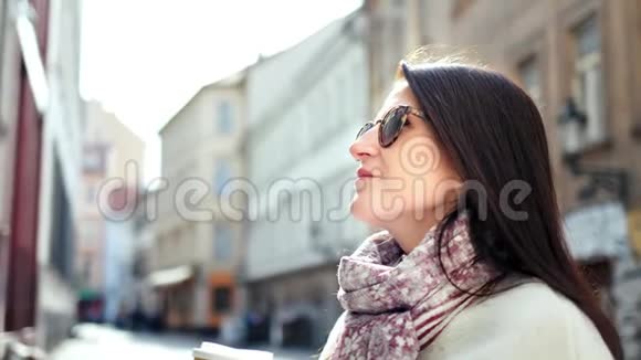 微笑时尚的旅行女孩太阳镜在狭窄的街道上享受休息拿着纸咖啡杯视频的预览图