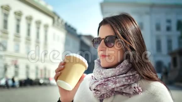 时尚女性从纸杯中喝咖啡在户外城市景观中享受休息视频的预览图