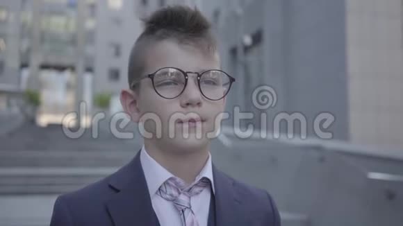 肖像英俊衣着考究戴眼镜的男孩站在街上看镜头严重的孩子面前视频的预览图