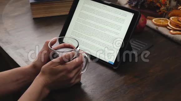 女人手里拿着杯子两手拿着覆盖着的酒在平板上看书视频的预览图